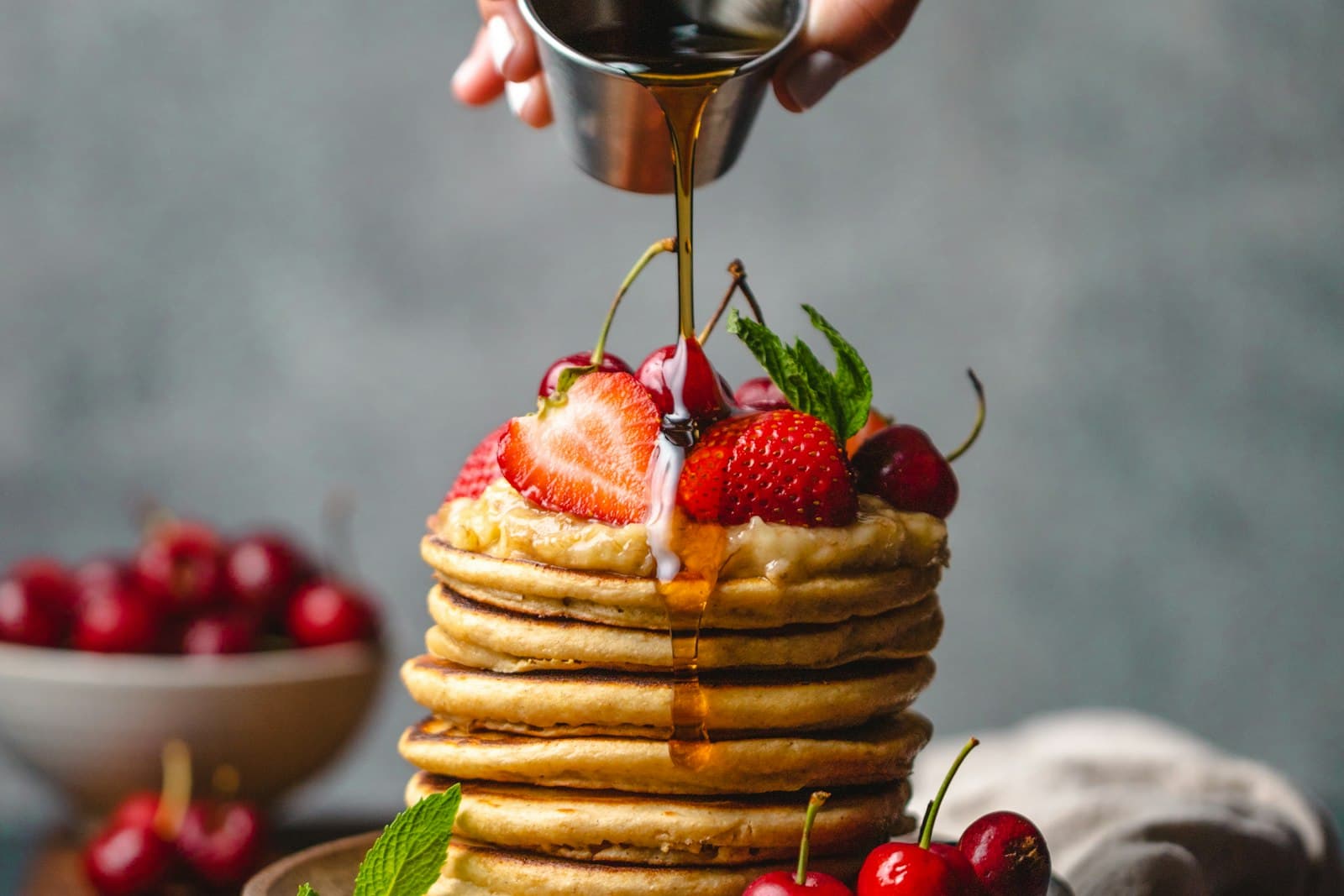 Stack of fluffy pancakes topped with strawberries and cherries