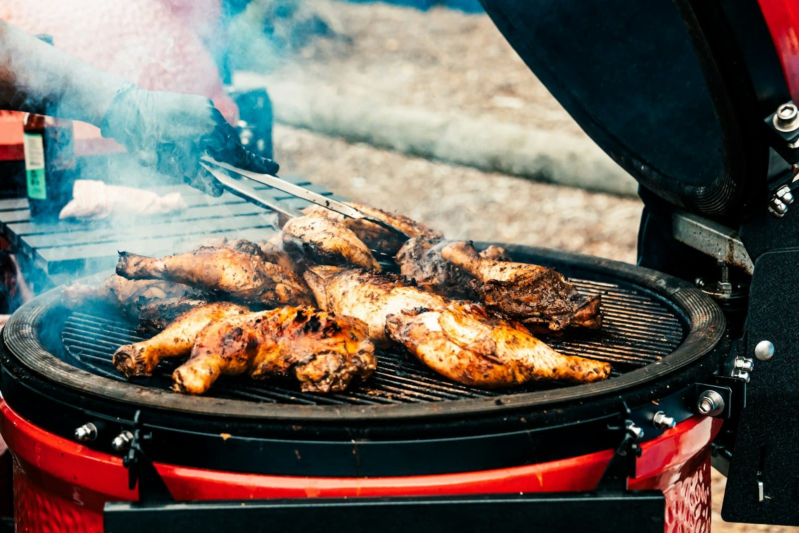 Spice-crusted jerk chicken leg quarters charring on a smoking round grill