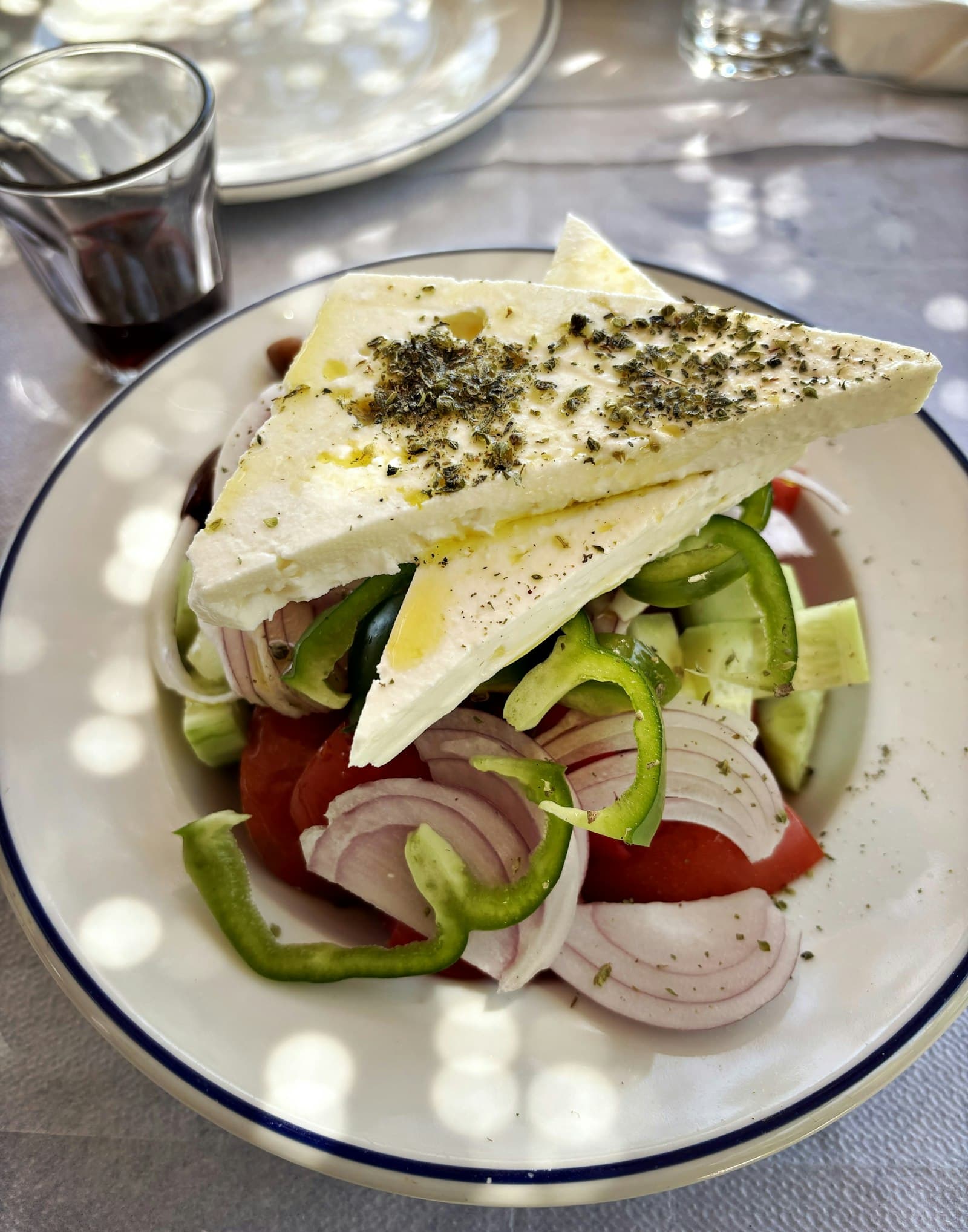 Greek salad of tomato, cucumber, green pepper and red onion topped with two triangles of feta sprinkled with dried oregano