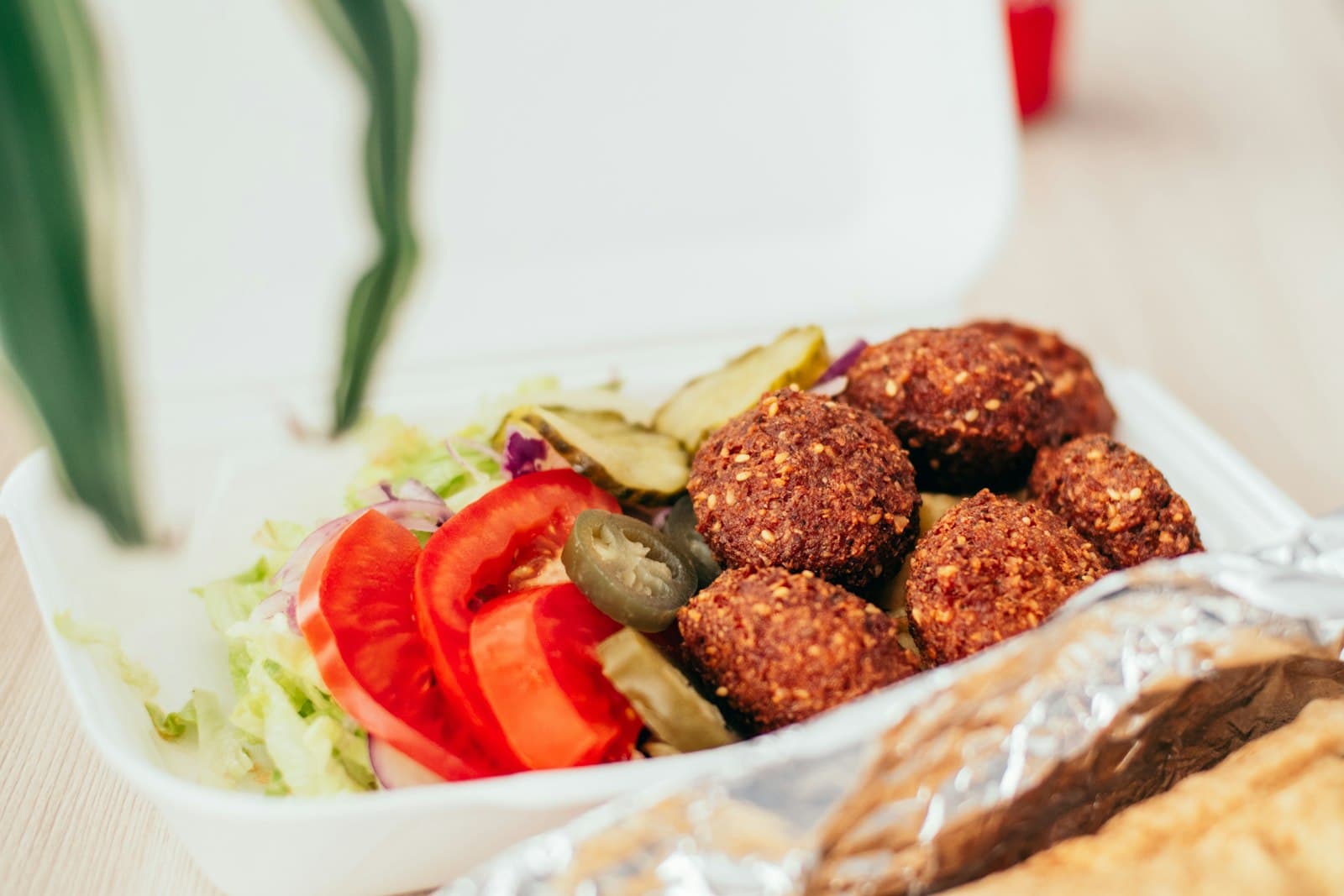 Golden falafel served with tomato slices, pickles and shredded lettuce