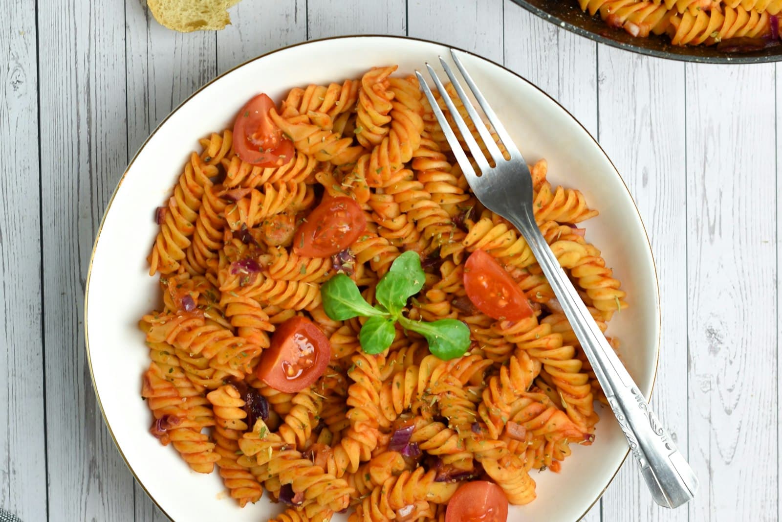 One-pot fusilli pasta in tomato sauce with cherry tomatoes and fresh basil in a white bowl